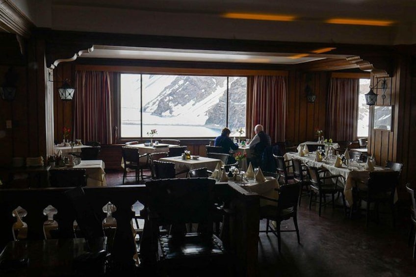 En restaurant med dækkede borde, et stort vindue med udsigt til sneklædte bjerge og træpaneler på væggene. 5