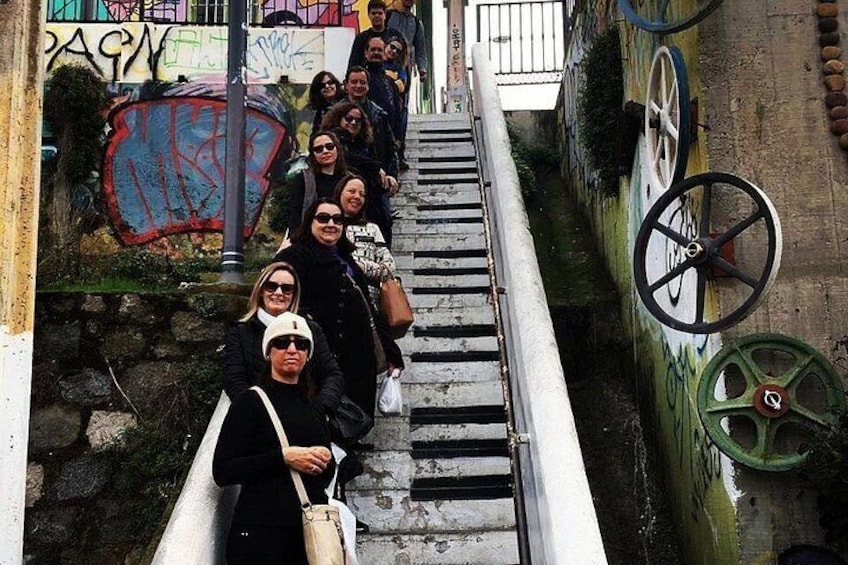 A group of people descending a narrow staircase with graffiti on the walls. 4