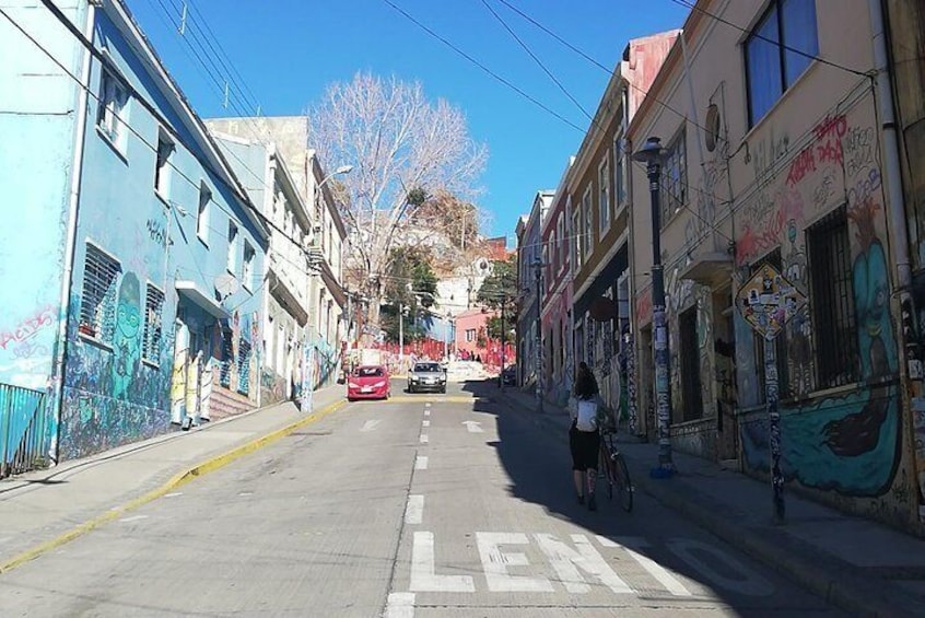 Una strada fiancheggiata da edifici, alcuni dei quali con graffiti. 2
