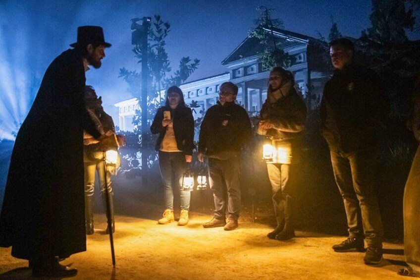 A group of people standing in a line with lanterns, a building in the background, and trees. 4