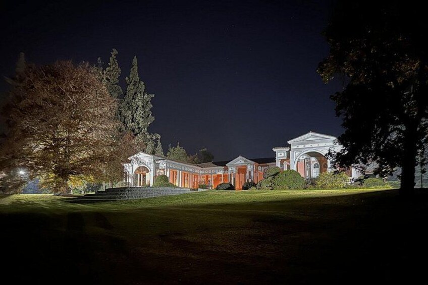 A large, illuminated building at night with a well-maintained lawn and trees. 5