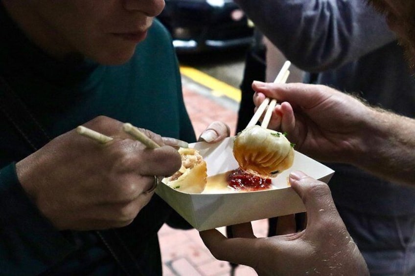 A person holding a food item with chopsticks. 1