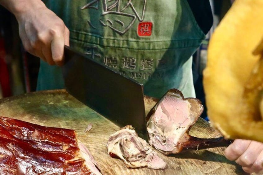 A person slicing meat on a wooden cutting board. 5