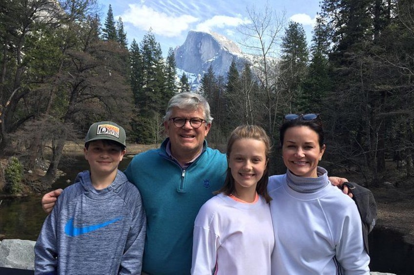 A family of four standing in a forested area with a mountain in the background. 5