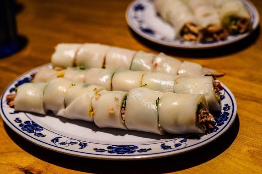 A plate of spring rolls with a floral pattern on the rim. 2