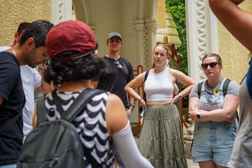 A group of people standing outdoors, some with backpacks, near a building with columns. 2