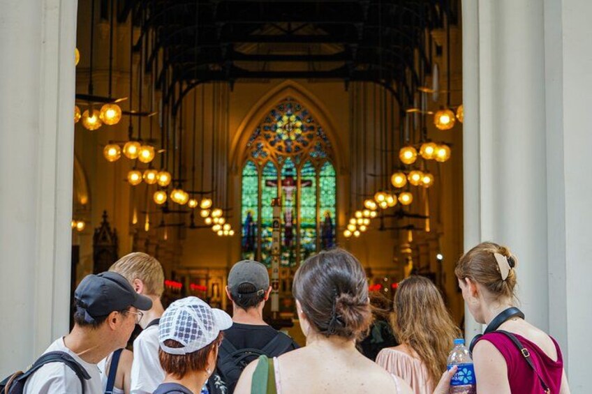 A group of people standing in front of a church with a large stained glass window. 3