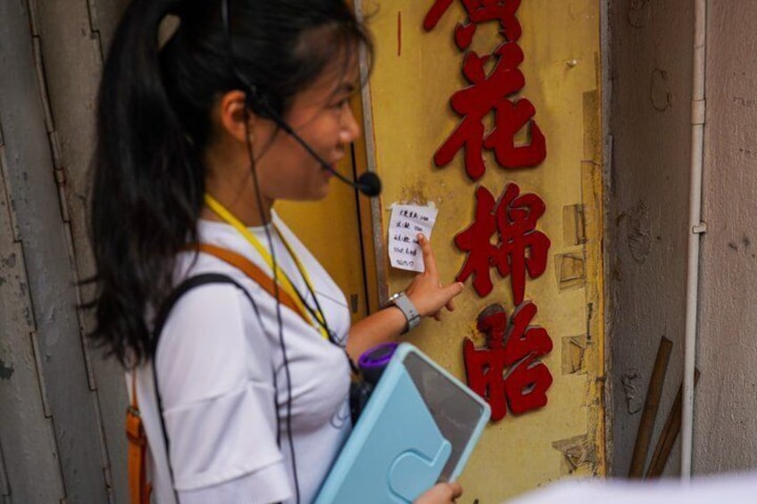 A person holding a blue folder and a white sign, standing in front of a yellow door with red Chinese characters. 2