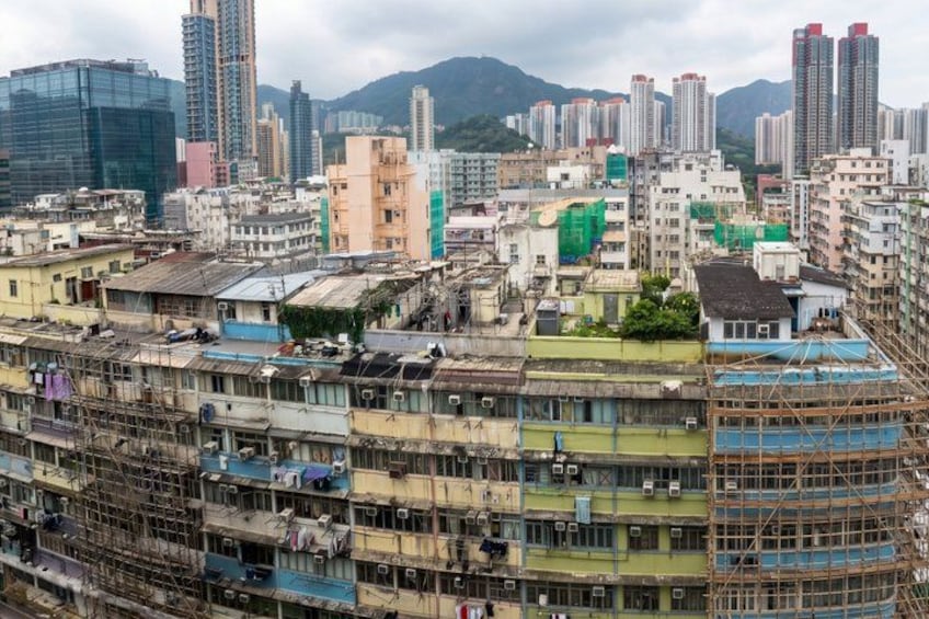 Una zona urbana densamente poblada con edificios de varios pisos, algunos en construcción, y montañas al fondo. 2