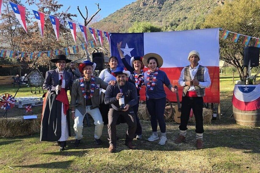 A group of people in front of a Texas flag, some wearing traditional attire, with a mountainous backdrop. 3