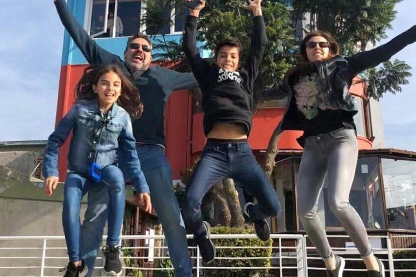 Un grupo de personas saltando en el aire, un edificio con fachada roja y azul, y una valla metálica. 2