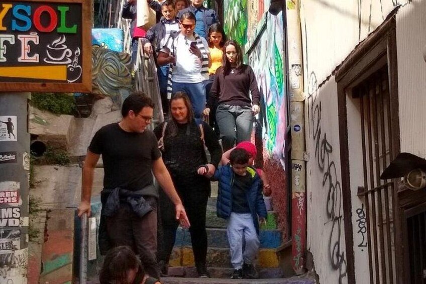 Un callejón estrecho con grafitis, una persona bajando unas escaleras, y un niño con una chaqueta azul. 3