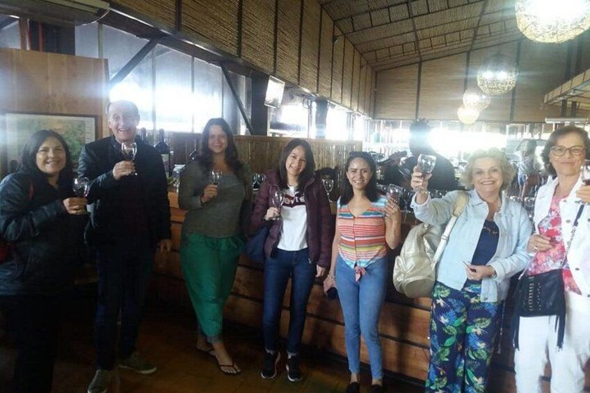 Un grupo de personas de pie en el interior, sosteniendo copas de vino, con una decoración de madera e iluminación colgante. 5