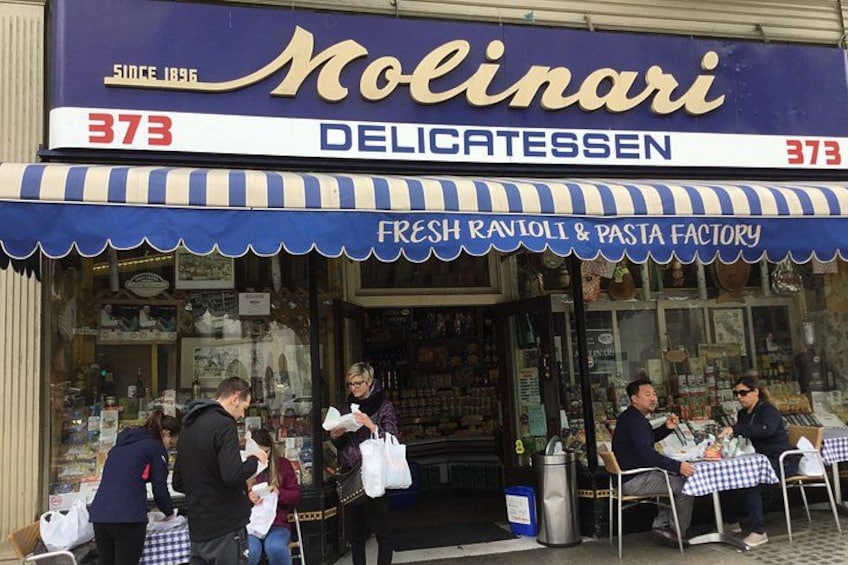 A storefront with a blue awning, a sign reading 'Nolinari Delicatessen,' and a number '373.' 2