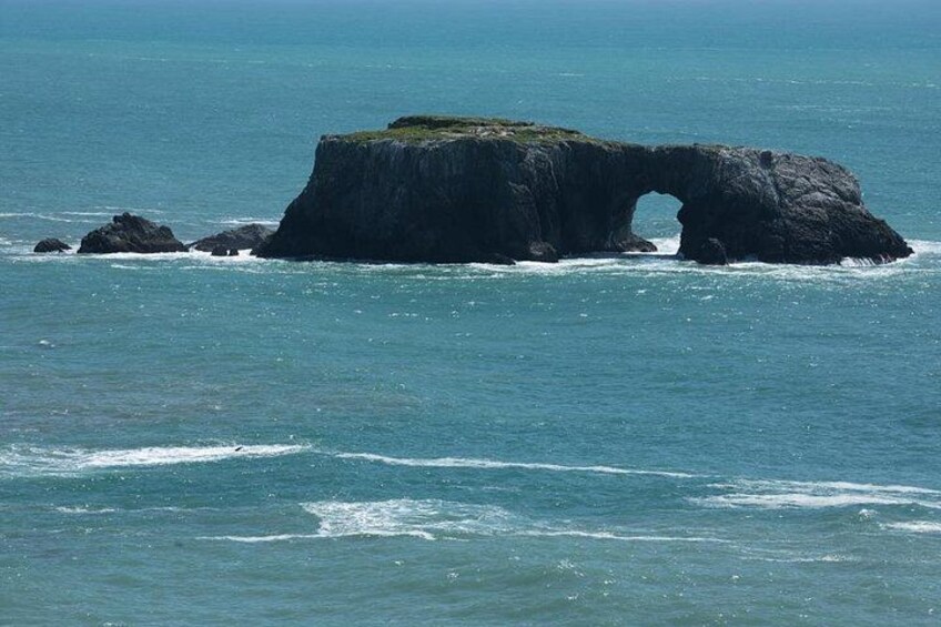 A large rock formation with a natural arch in the ocean. 3