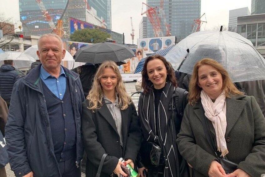 Un grupo de personas de pie al aire libre, sosteniendo paraguas, en un entorno urbano con edificios y grúas de construcción al fondo. 3