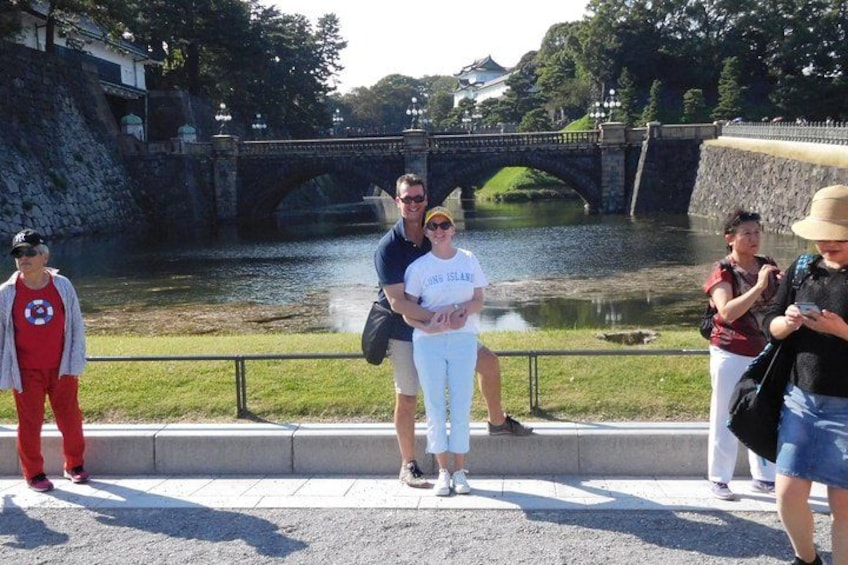 A group of people standing by a river with a bridge in the background. 3