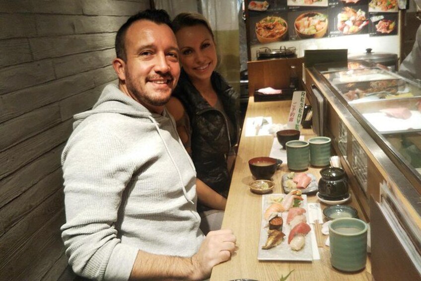 En restauranginteriör med träväggar, ett fat med sushi och ett glasmontrinskåp. 2