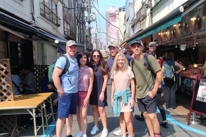 A group of people standing on a street with buildings and shops in the background. 2