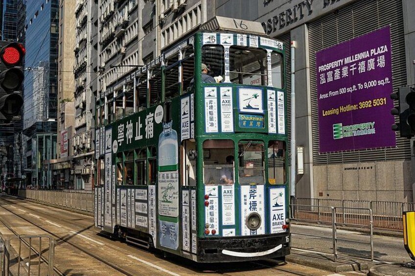 Un tranvía verde de dos pisos en una calle de la ciudad, con anuncios publicitarios a los lados. 2