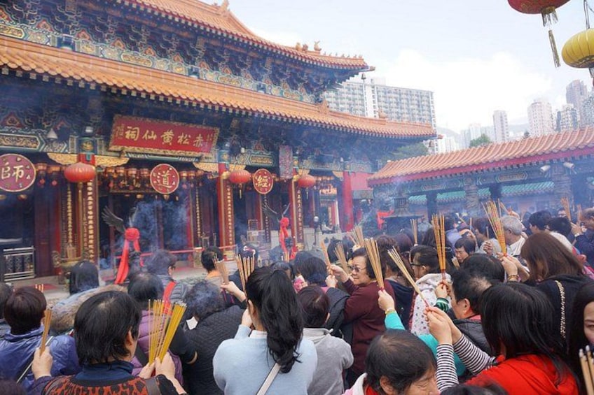 Un templo chino tradicional con arquitectura ornamentada, una multitud de personas y palitos de incienso. 5