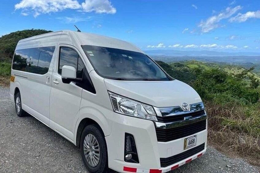 A white van parked on a gravel road with a scenic view of hills and a clear sky in the background. 2