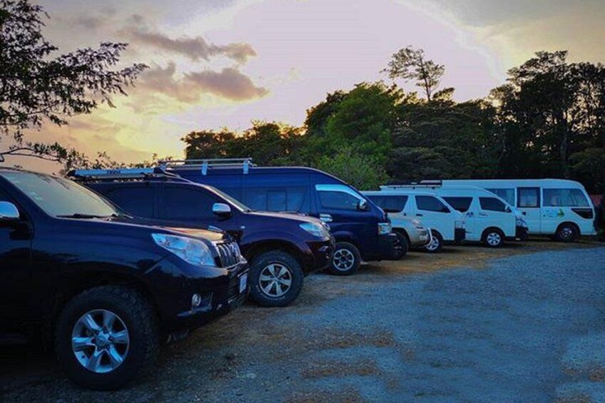 A parking lot with several SUVs and a white bus. 5