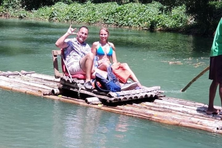 Two people on a floating platform in a river surrounded by greenery. 3