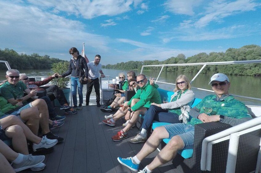 A group of people on a boat with a river and trees in the background. 1