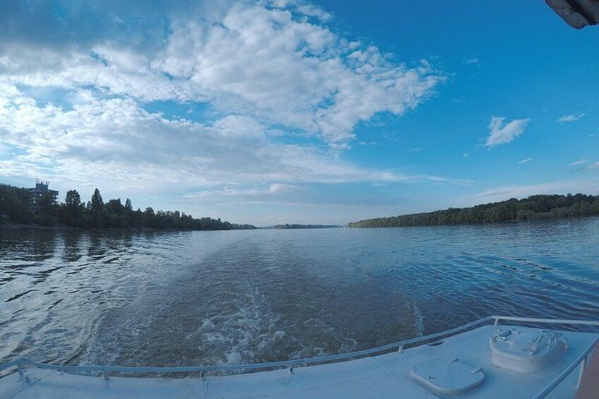 A boat on a calm river with a clear sky and distant trees. 4