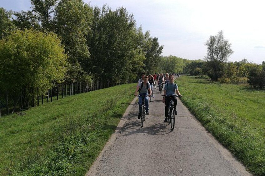 A group of cyclists on a paved path surrounded by greenery. 2