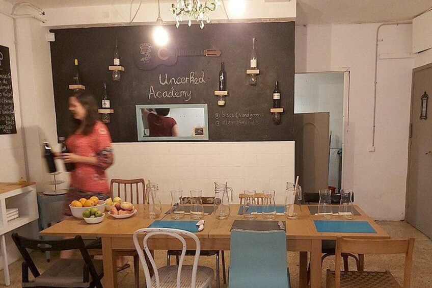 A dining area with a blackboard, bottles, and a bowl of fruit. 2
