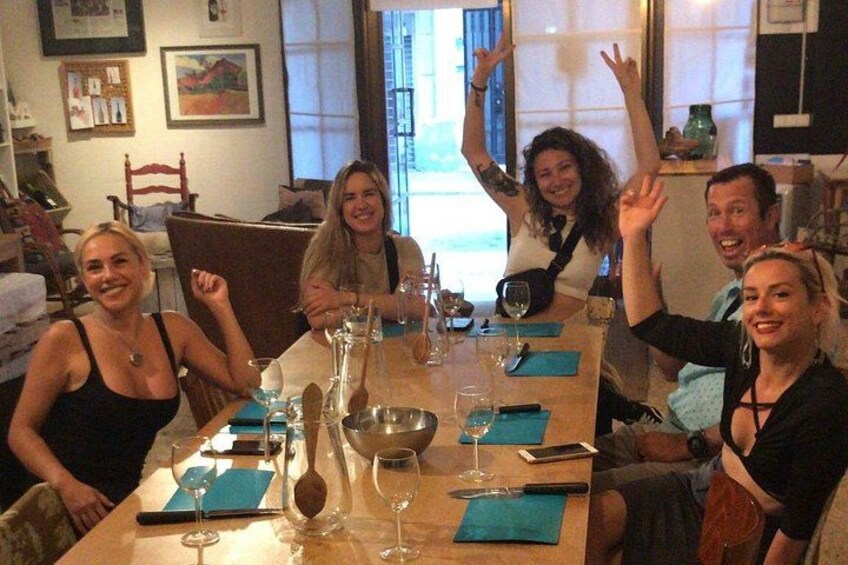 A group of people sitting around a table with wine glasses and a bowl. 2