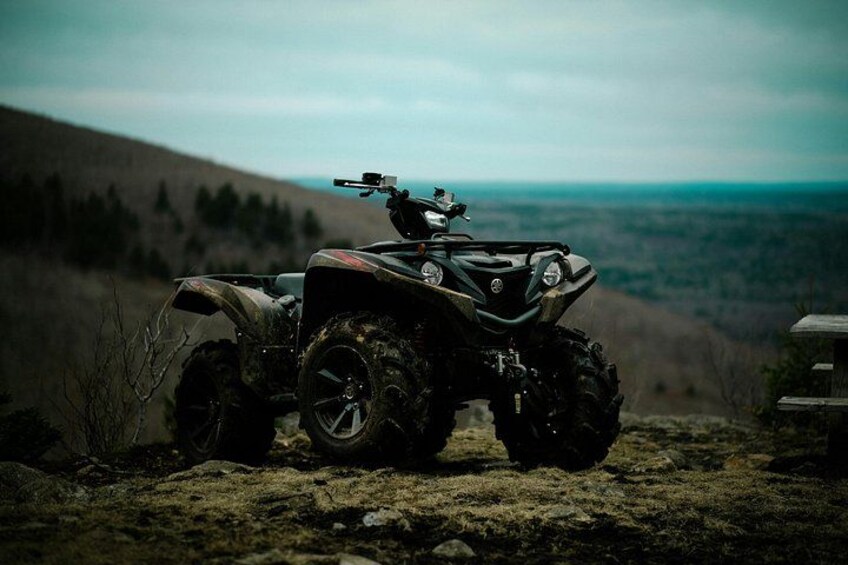 En ATV holder parkeret på et klippefyldt terræn med et bjerglandskab i baggrunden. 3