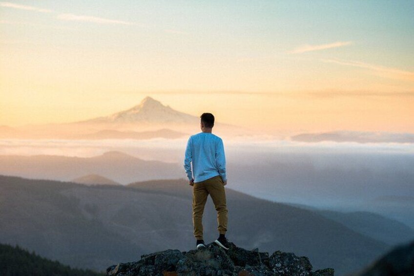 Eine Person steht auf einem Berggipfel, im Hintergrund ein Berg. 4