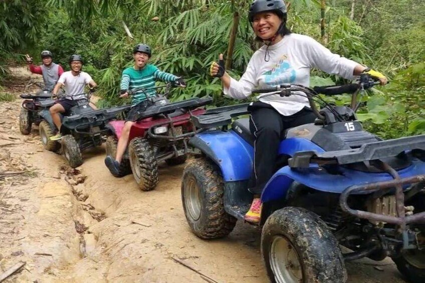 A group of people on ATVs on a dirt path surrounded by greenery. 1