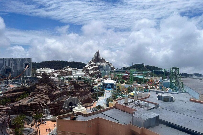 A theme park with roller coasters, a large mountain-like structure, and a body of water. 3