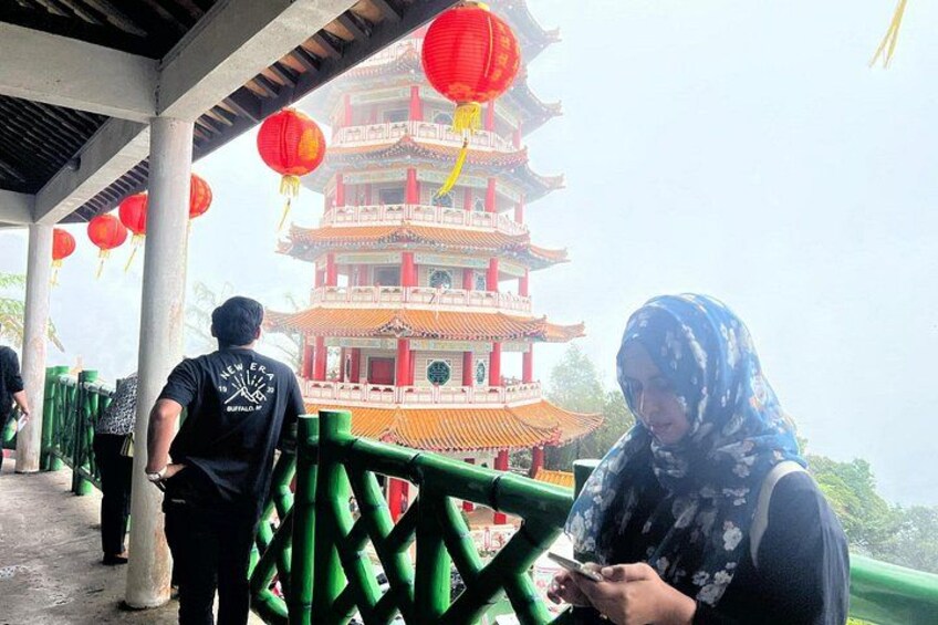 A pagoda with red lanterns, a person in a black shirt, and another person in a patterned headscarf. 5