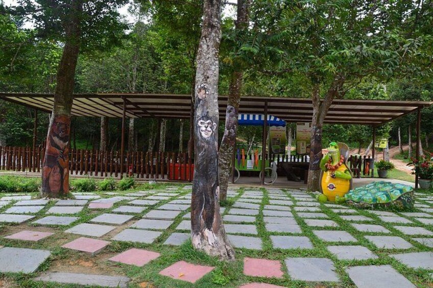 A park with a paved walkway, trees, and a covered area with a blue roof. 5