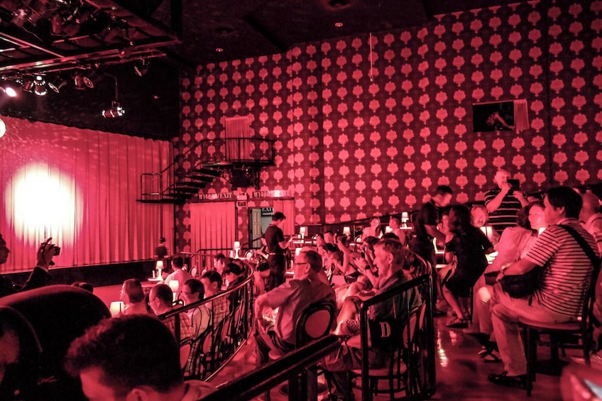A crowded bar with a patterned wall and a staircase. 3