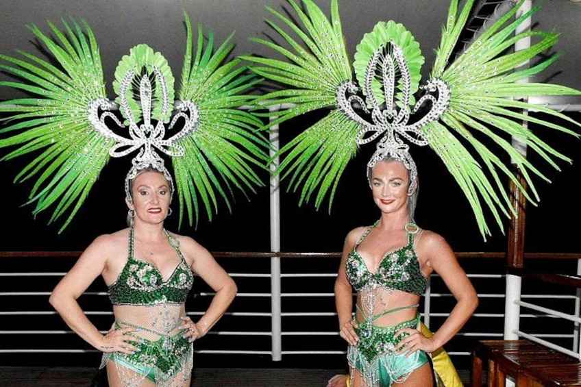 Two performers in green costumes with elaborate headdresses. 2