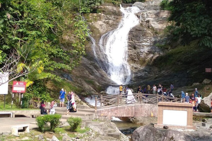 A waterfall, a wooden bridge, and people observing the scenery. 2