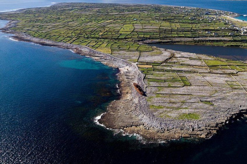An aerial view of a coastal area with terraced fields, a rocky shoreline, and a body of water. 3