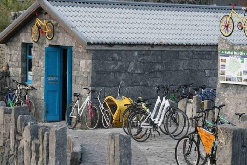 A stone building with a blue door, bicycles parked in front, and a sign with a map. 2