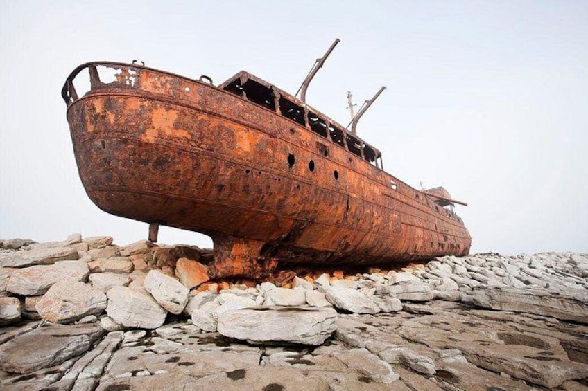 A rusted shipwreck on a rocky shore. 4