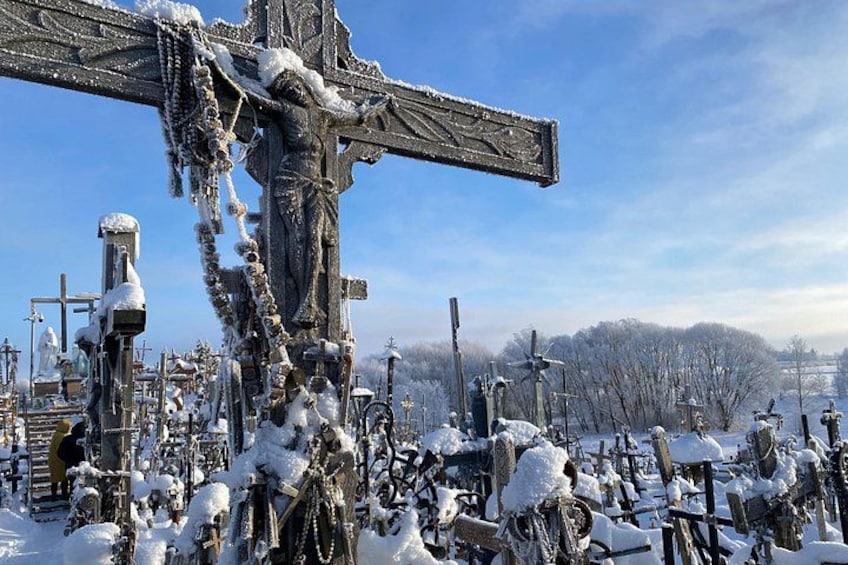 Een met sneeuw bedekte begraafplaats met een opvallend kruis en grafstenen. 3