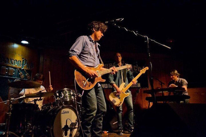 Una banda tocando en el escenario, con una batería y un teclado al fondo. 4