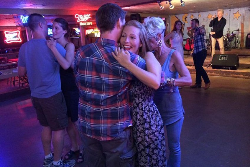 Folk danser i et dunkelt lokale med neonskilte. 3