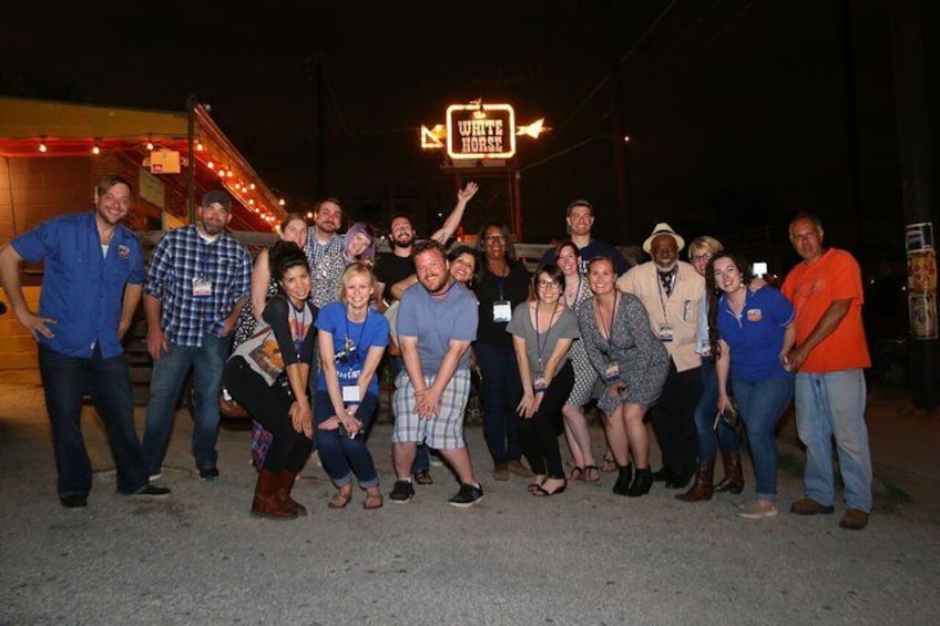 A group of people posing for a photo in front of a building with a sign that reads 'White Horse.' 3