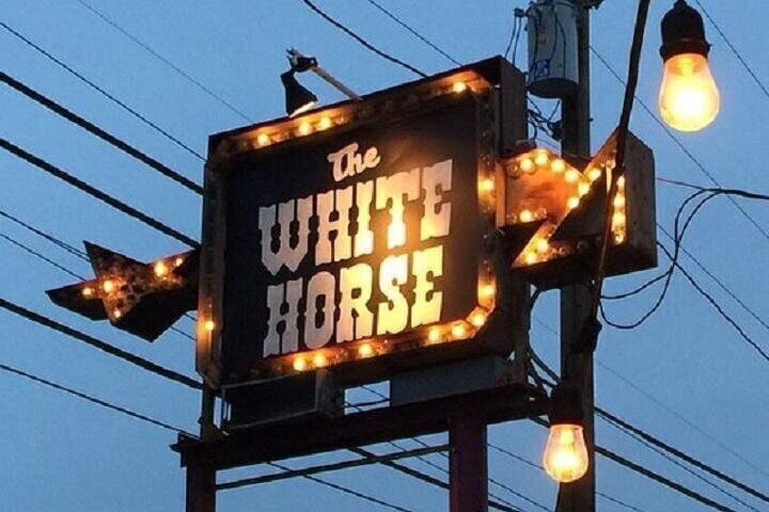 Un letrero de neón para 'The White Horse' con bombillas alrededor. 2